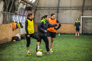 A football coach speaking to two players on the football field