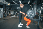 A gym instructor helping a client lifting weights