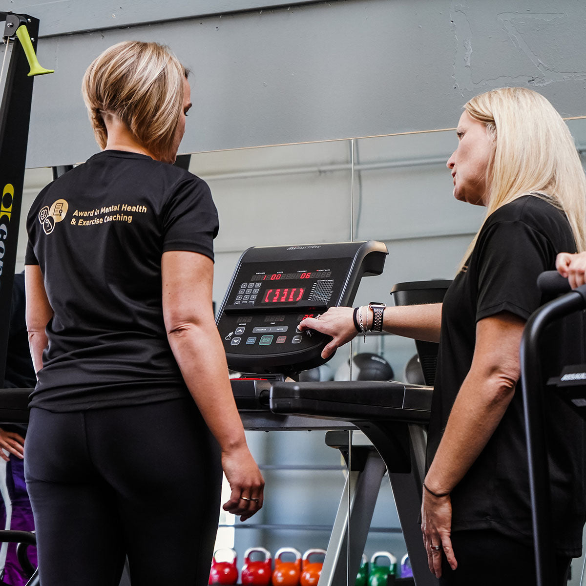 A personal trainer supporting someone on a treadmill