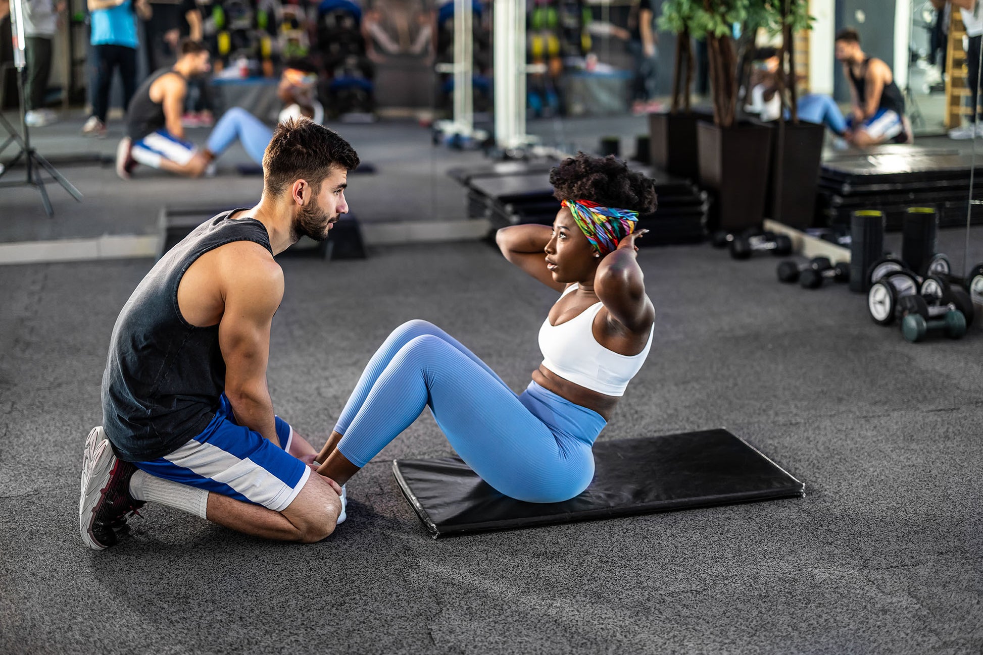 A personal trainer holding their client's feet while they do a sit up