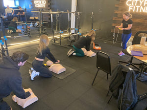 A group of people practising CPR on dummies. 