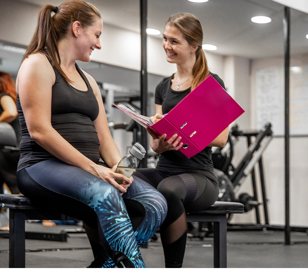 A gym instructor talking to a gym goer