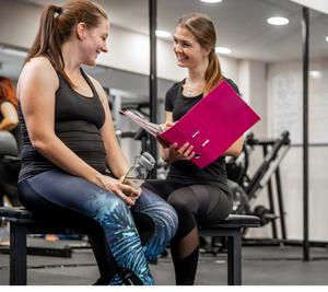 A gym instructor talking to a gym goer