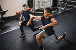 A personal trainer coaching a gym goer on their lunge technique