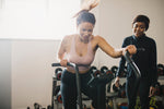 A gym instructor coaching a person on using an exercise machine