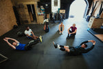 A group of people exercising in a gym following a gym instructor