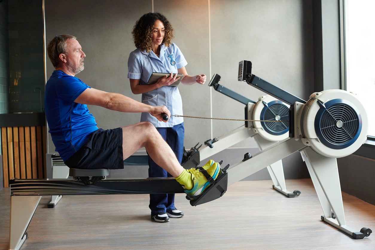 A nurse helping a person on a rowing machine