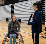 A coach speaking to a wheelchair basketball player