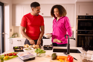 Two people in fitness clothing making a batch of healthy meals in advance