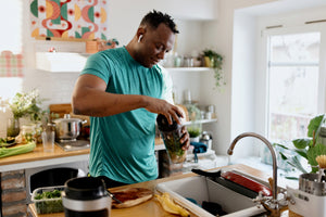 A person making a healthy smoothie in a kitchen in their gym clothes