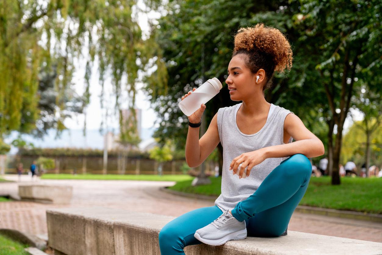 Female runner at the park taking a break to drink some water