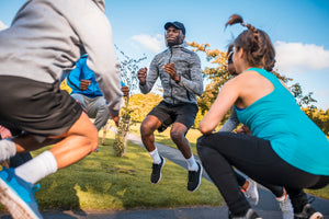 A group of people exercising and jumping outdoors in a park on a sunny day.