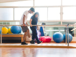 A physiotherapist helping a client to walk using bars