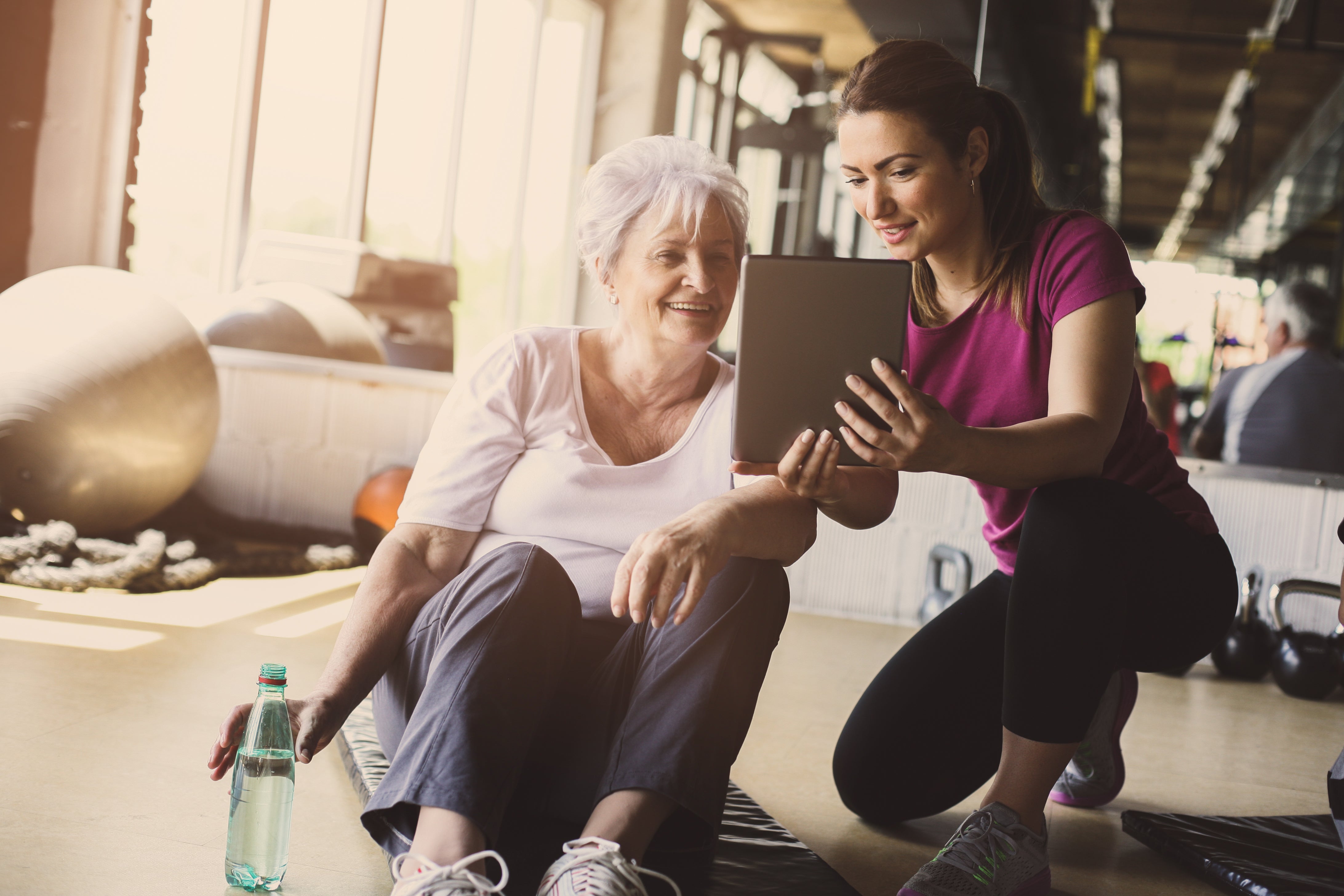 A personal trainer showing a client their progress on an tablet