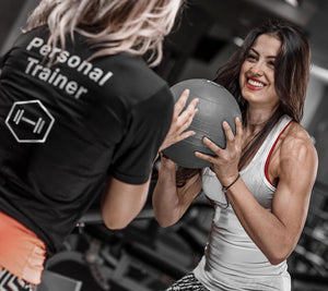 A personal trainer working with their client with a weighted ball